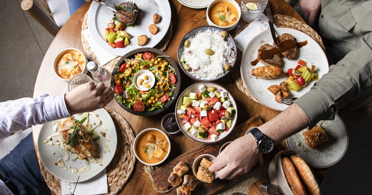 Colourful family dinner table with various dishes, salads, and fresh bread