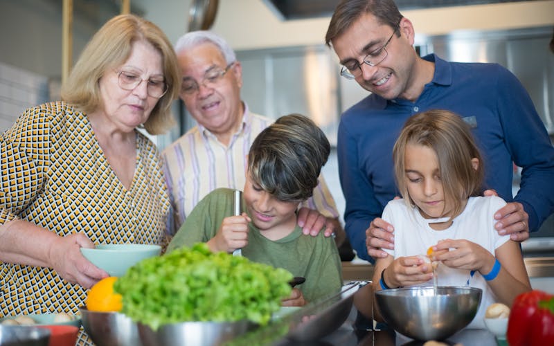 Familie kocht gemeinsam in der Küche — Eltern und Kinder bereiten zusammen ein Abendessen vor