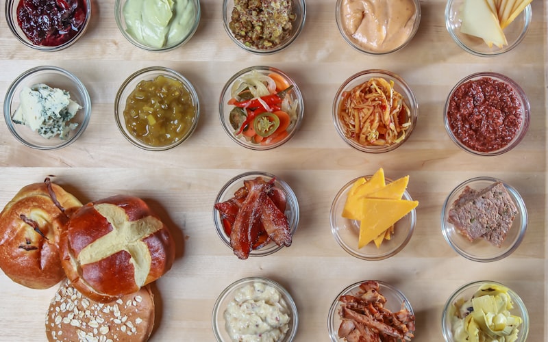 Raclette-Zutaten übersichtlich auf einem Holzbrett angerichtet: Käse, Kartoffeln, Cornichons, Gemüse und Trockenfleisch